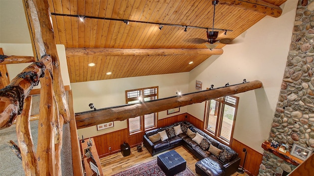 living room with vaulted ceiling with beams, wooden ceiling, and wooden walls