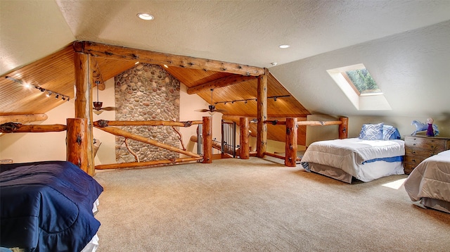 bedroom featuring carpet flooring, vaulted ceiling with skylight, rail lighting, and a textured ceiling