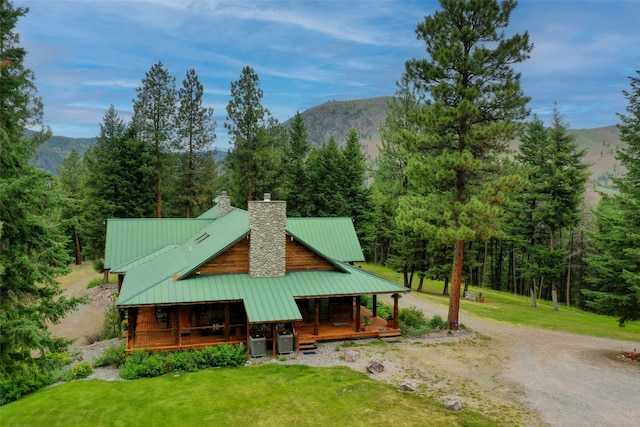 rear view of house featuring central AC, a mountain view, a yard, and covered porch