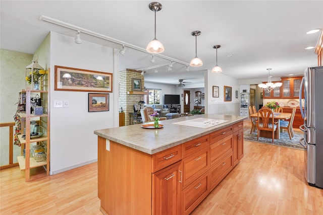 kitchen featuring pendant lighting, rail lighting, a kitchen island, light hardwood / wood-style flooring, and stainless steel refrigerator