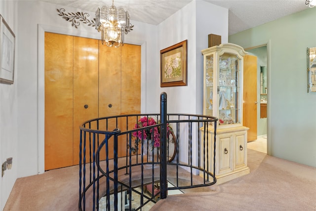 corridor featuring a chandelier, light carpet, and a textured ceiling