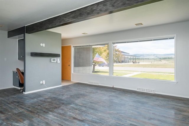 unfurnished living room featuring dark hardwood / wood-style flooring and a mountain view