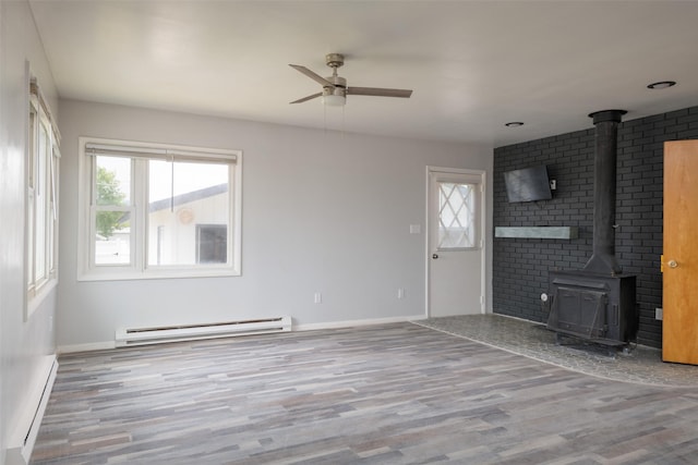 unfurnished living room featuring a baseboard heating unit, hardwood / wood-style flooring, ceiling fan, and a wood stove