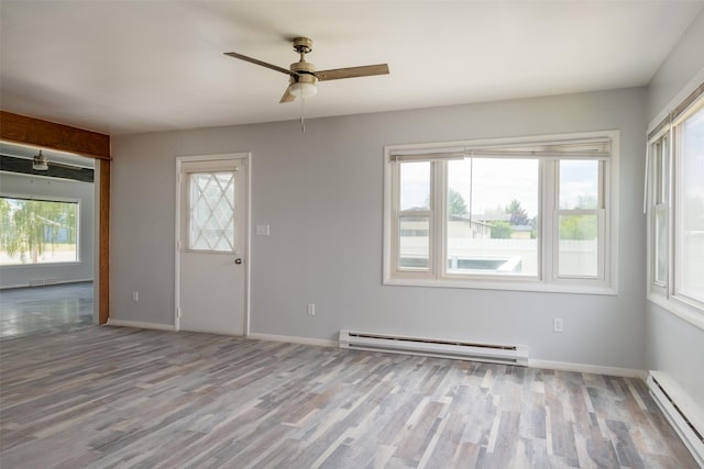 empty room featuring plenty of natural light, light wood-type flooring, and baseboard heating