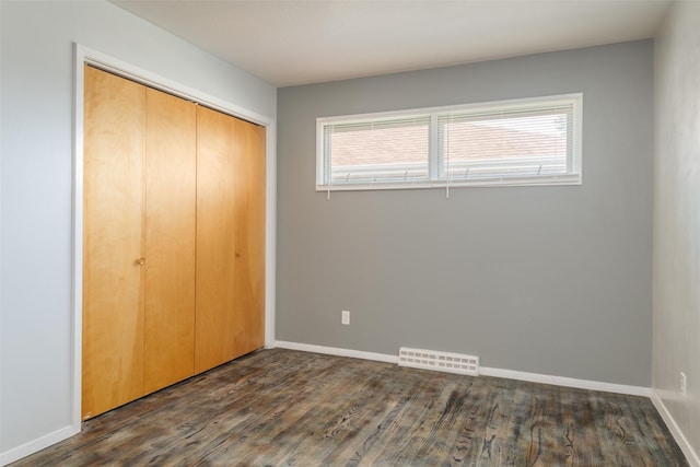 unfurnished bedroom featuring dark hardwood / wood-style floors and a closet