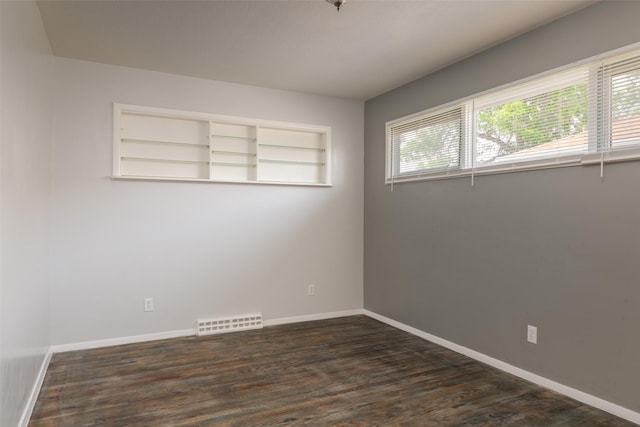 spare room featuring dark wood-type flooring and built in features