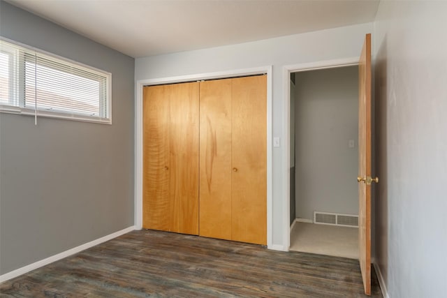 unfurnished bedroom featuring dark wood-type flooring and a closet