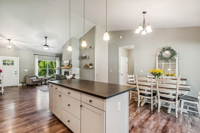 kitchen featuring dark wood-type flooring, white cabinetry, decorative light fixtures, a fireplace, and ceiling fan with notable chandelier