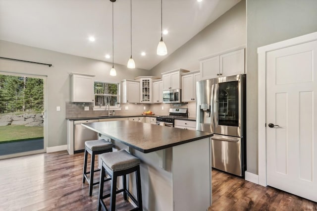 kitchen with a kitchen island, tasteful backsplash, white cabinetry, hanging light fixtures, and stainless steel appliances