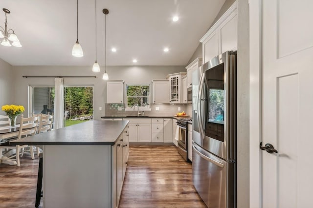 kitchen featuring pendant lighting, sink, appliances with stainless steel finishes, white cabinetry, and a center island