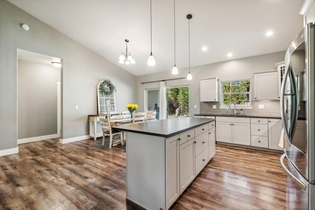 kitchen with a kitchen island, pendant lighting, sink, white cabinets, and stainless steel fridge