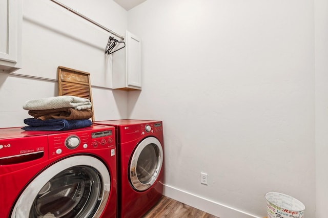 washroom with hardwood / wood-style flooring, cabinets, and washing machine and dryer