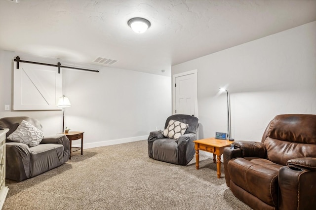 sitting room with light colored carpet, a barn door, and a textured ceiling