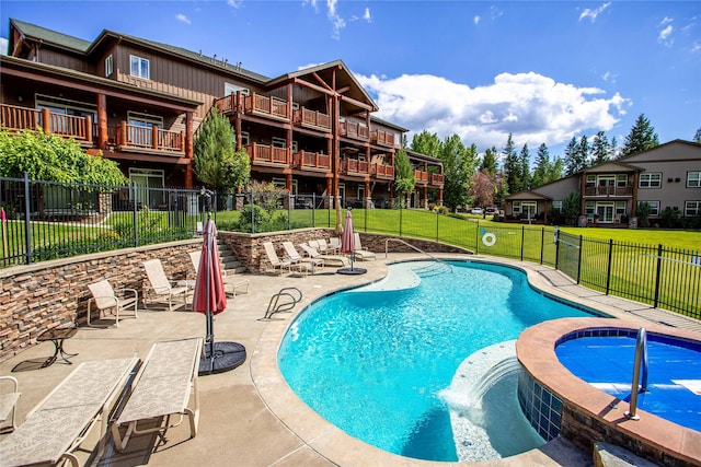 view of swimming pool featuring a community hot tub, a lawn, and a patio