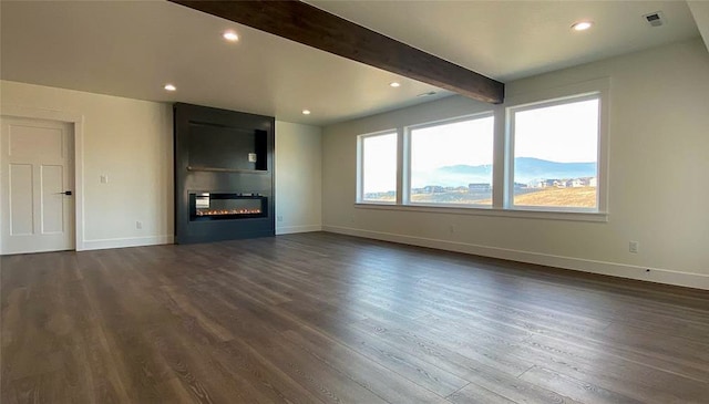 unfurnished living room featuring beam ceiling and dark wood-type flooring