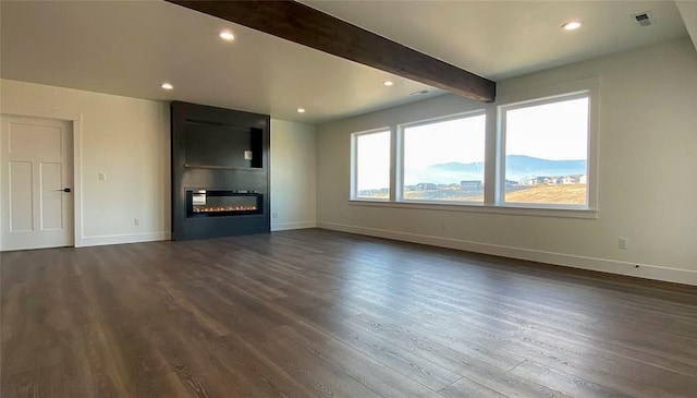 unfurnished living room featuring dark wood-type flooring, a glass covered fireplace, beamed ceiling, and baseboards