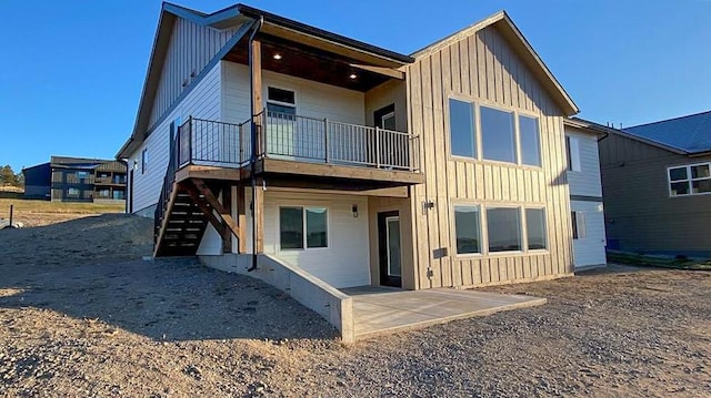 back of property featuring stairway, board and batten siding, and a patio area