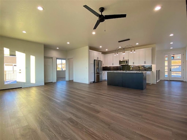 kitchen featuring dark wood-style floors, stainless steel appliances, open floor plan, white cabinets, and plenty of natural light