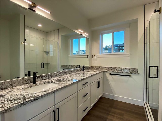 bathroom with walk in shower, dual vanity, and hardwood / wood-style floors