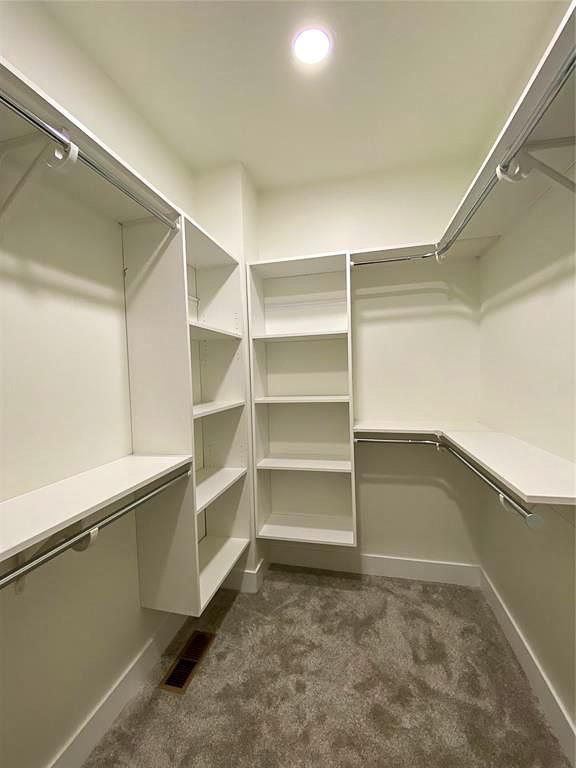 spacious closet with dark colored carpet and visible vents