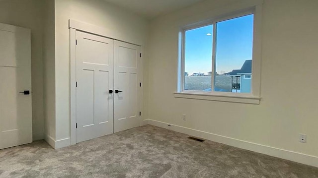 unfurnished bedroom with carpet, a closet, visible vents, and baseboards