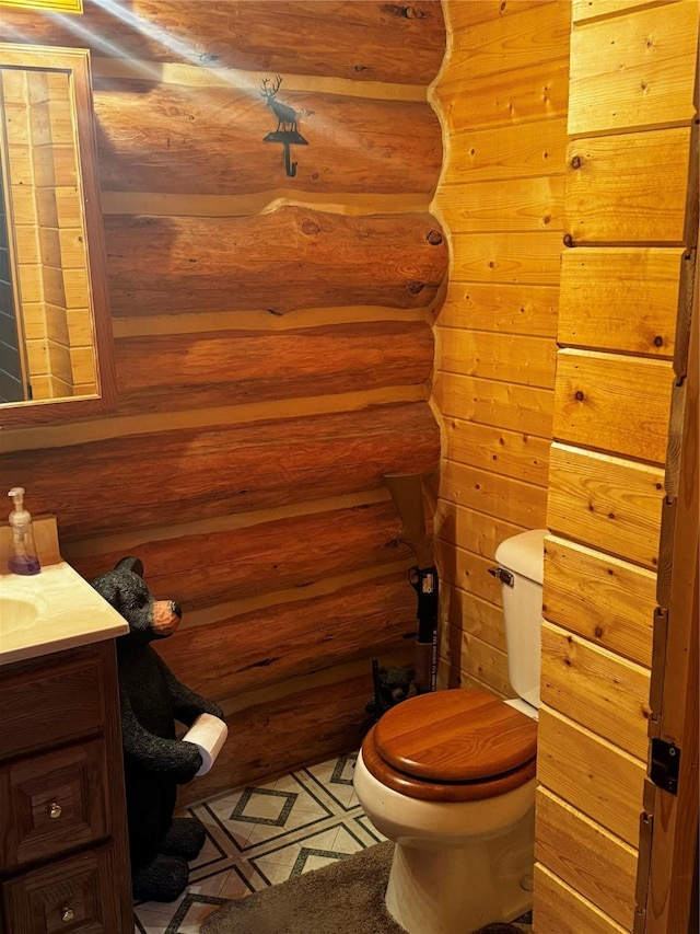 bathroom with vanity, log walls, toilet, and wood walls