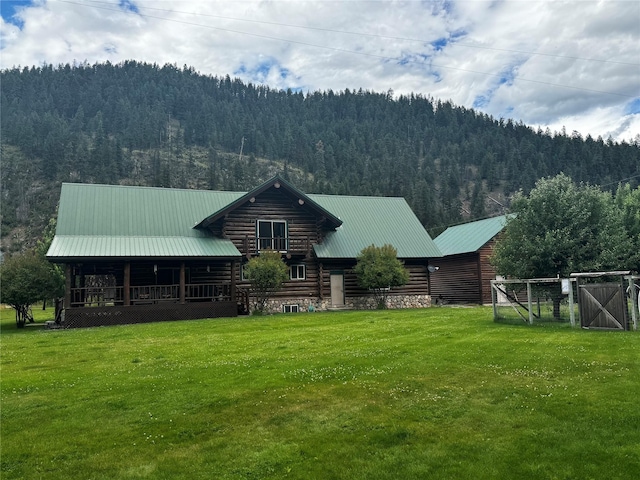 rear view of house with a mountain view and a lawn