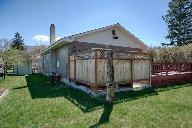 view of side of home with a deck, a shed, and a lawn