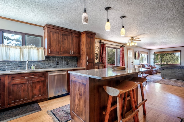 kitchen with stainless steel dishwasher, a textured ceiling, sink, and light wood-type flooring