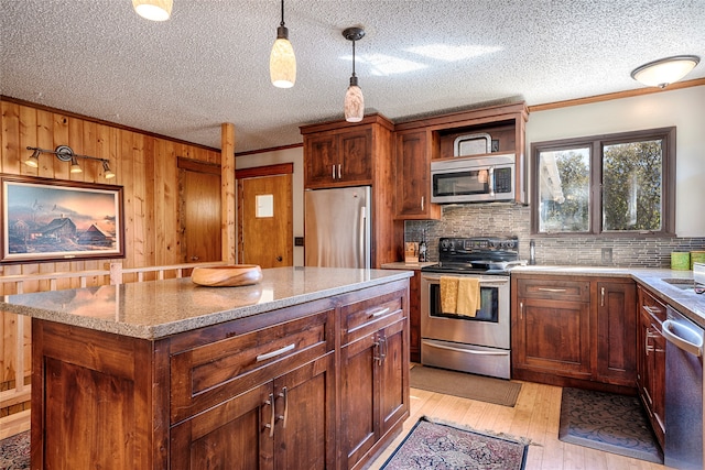 kitchen with stainless steel appliances, tasteful backsplash, hanging light fixtures, light hardwood / wood-style flooring, and a kitchen island