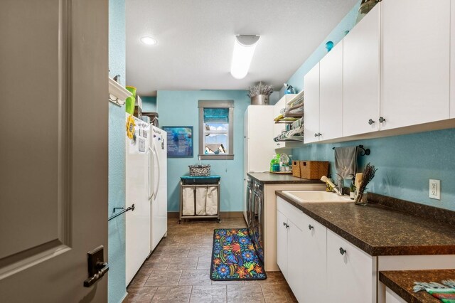 282 Mcwenneger Dr, Kalispell, MT 59901 - kitchen featuring white cabinets, dark countertops, washing machine and dryer, and stone finish floors