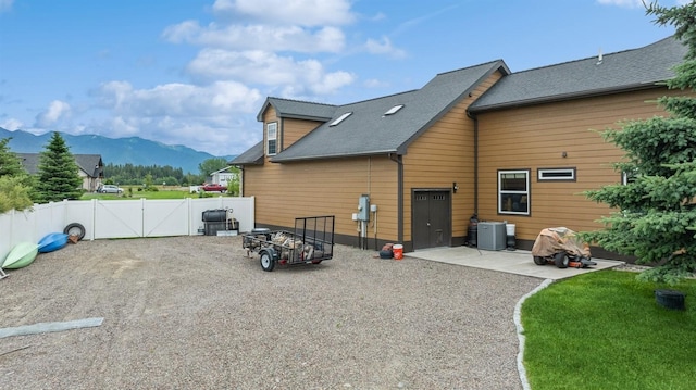 282 Mcwenneger Dr, Kalispell, MT 59901 - rear view of property featuring a mountain view, a gate, a patio area, and roof with shingles