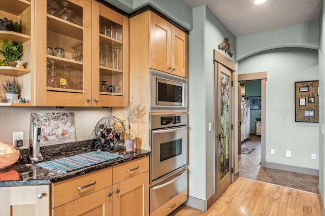 282 Mcwenneger Dr, Kalispell, MT 59901 - kitchen featuring stainless steel appliances, a warming drawer, dark stone countertops, light wood finished floors, and arched walkways