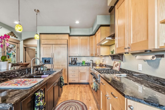 282 Mcwenneger Dr, Kalispell, MT 59901 - kitchen featuring high end stainless steel range oven, wall chimney range hood, light wood-style flooring, light brown cabinetry, and arched walkways