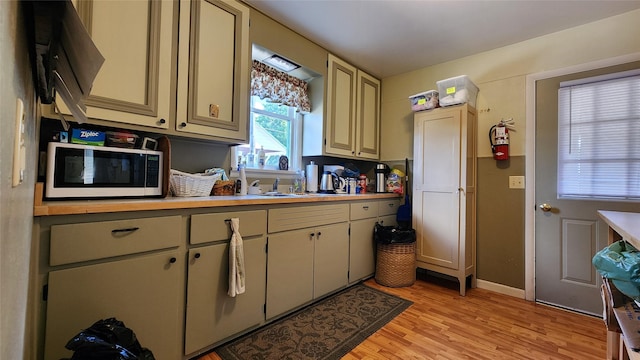 kitchen with cream cabinetry, light wood-type flooring, and sink