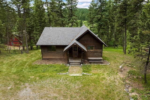 112 Glen View Dr, Eureka, MT 59917 - rustic home with a shingled roof, a forest view, and a front lawn