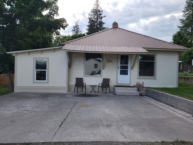 213 Washington St, Thompson Falls, MT 59873 - rear view of property featuring stucco siding, a porch, metal roof, and fence