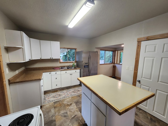 kitchen with range, a kitchen island, white cabinetry, and stainless steel refrigerator with ice dispenser