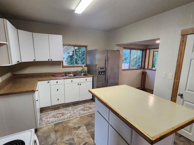 213 Washington St, Thompson Falls, MT 59873 - kitchen featuring plenty of natural light, stainless steel fridge with ice dispenser, a sink, stone finish flooring, and white cabinetry