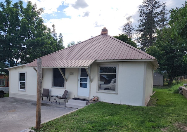 213 Washington St, Thompson Falls, MT 59873 - rear view of house with stucco siding, a yard, and metal roof