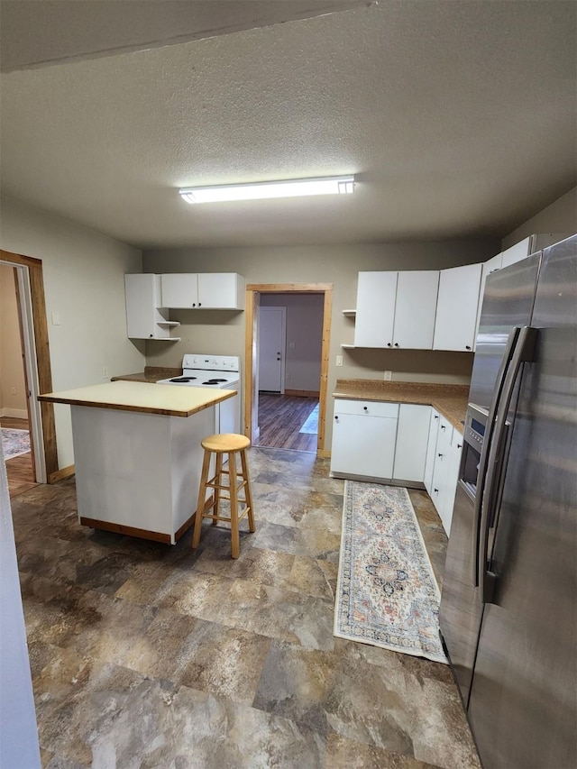 213 Washington St, Thompson Falls, MT 59873 - kitchen with stone finish flooring, baseboards, white cabinetry, and stainless steel fridge