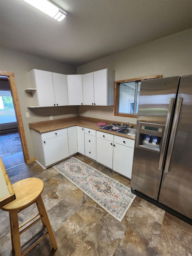 kitchen featuring stainless steel fridge, tile patterned floors, and white cabinets