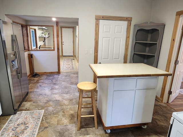 kitchen with tile patterned flooring, white cabinetry, a kitchen island, and stainless steel refrigerator with ice dispenser