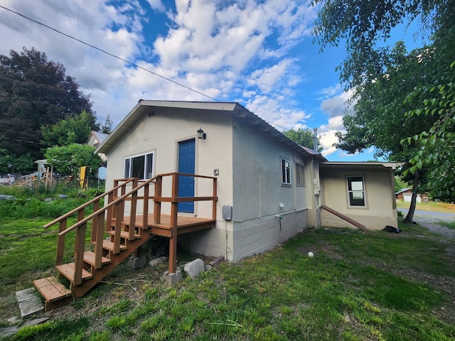 back of property with a deck and a lawn