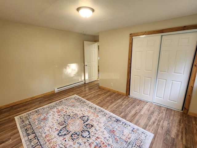 unfurnished bedroom with a baseboard radiator, a closet, and wood-type flooring