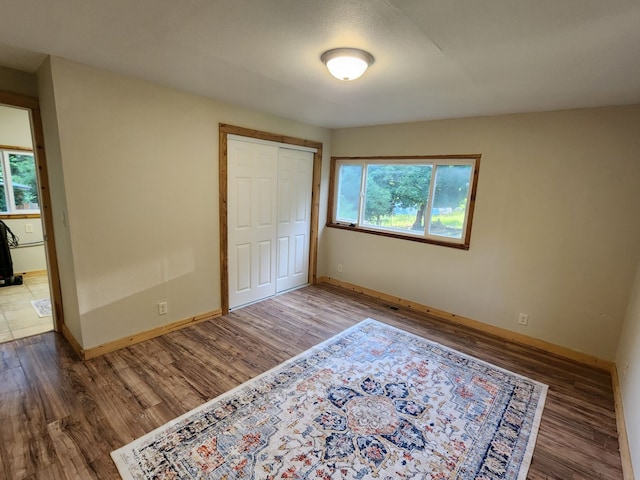 unfurnished bedroom featuring multiple windows, hardwood / wood-style flooring, and a closet