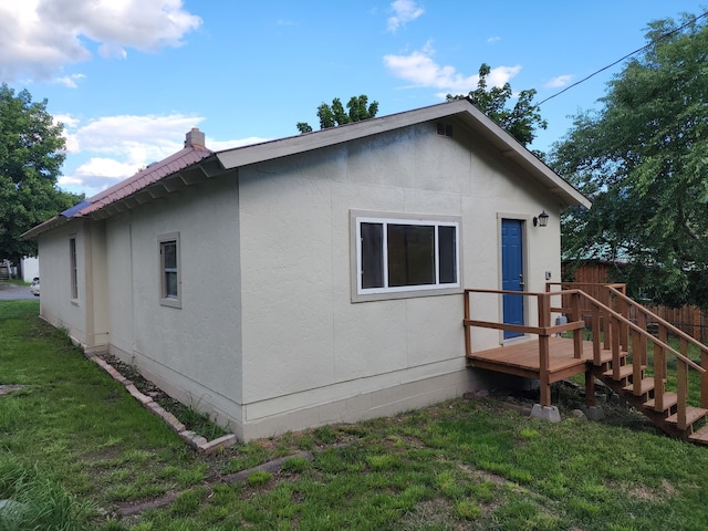 view of property exterior featuring a wooden deck and a lawn