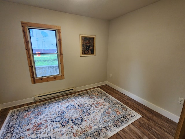 unfurnished room with a baseboard heating unit and dark hardwood / wood-style flooring