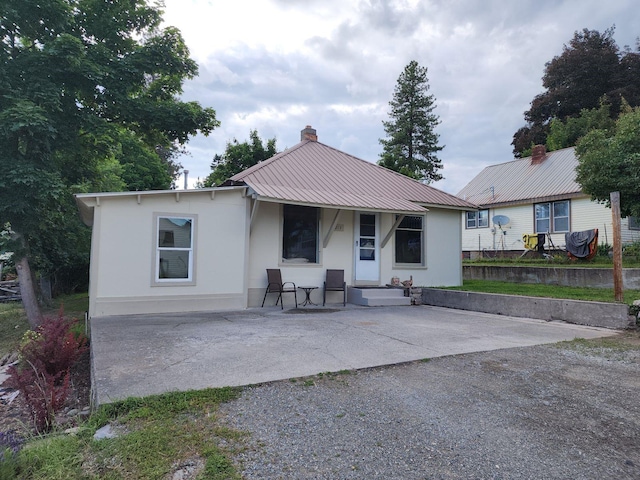 213 Washington St, Thompson Falls, MT 59873 - back of house featuring metal roof, a porch, a chimney, and stucco siding