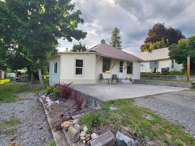 213 Washington St, Thompson Falls, MT 59873 - back of property with a chimney, gravel driveway, stucco siding, and metal roof